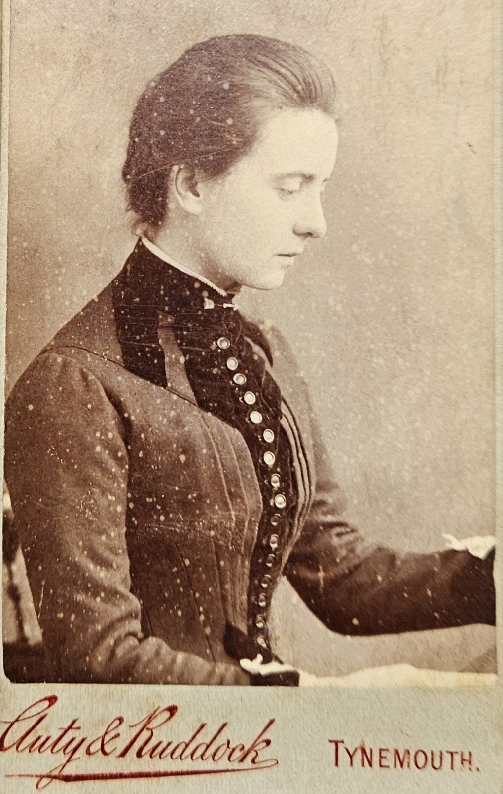 Profile portrait of a young woman in a vintage dress, looking to the side with a serious expression.