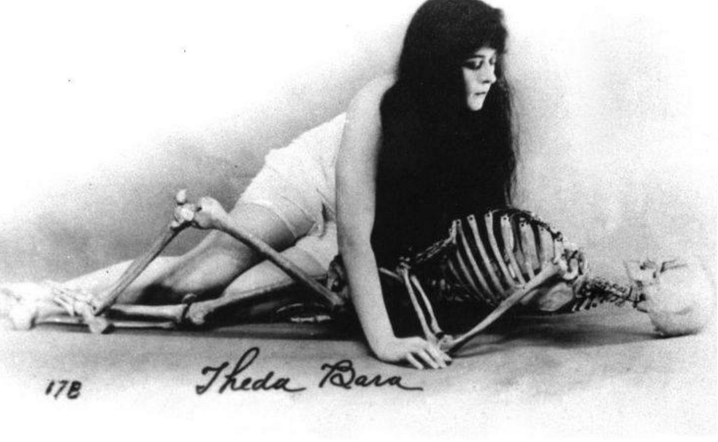 Black and white promotional photo of a half-clad Theda Bara posing with a human skeleton. Image recreates the tableau from Burne-Jones’ painting “The Vampire” Black and white promotional photo of a half-clad Theda Bara posing with a human skeleton. Image recreates the tableau from Burne-Jones’ painting “The Vampire”