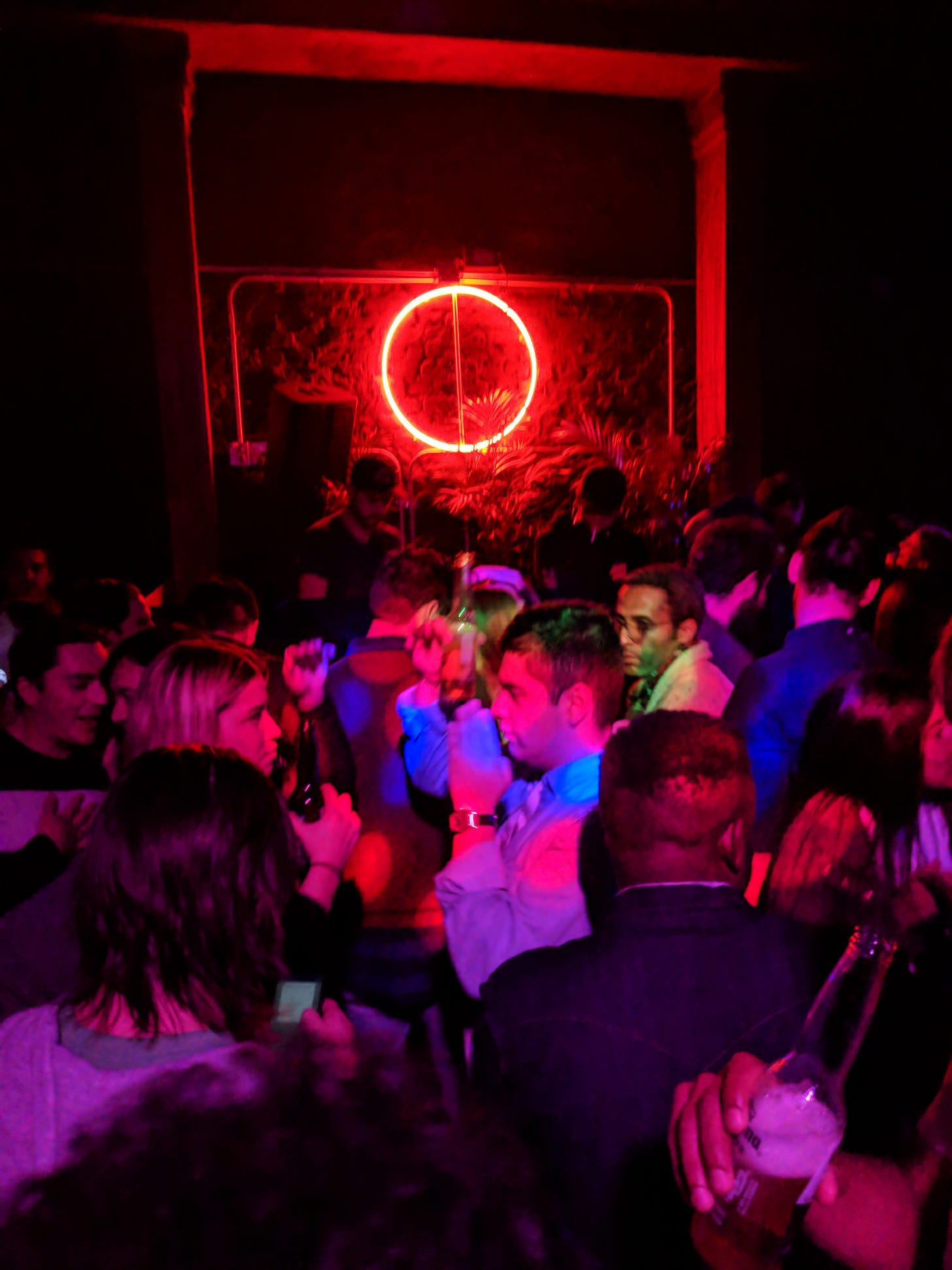 many people dancing to electronic music in a crowded club with neon lights
