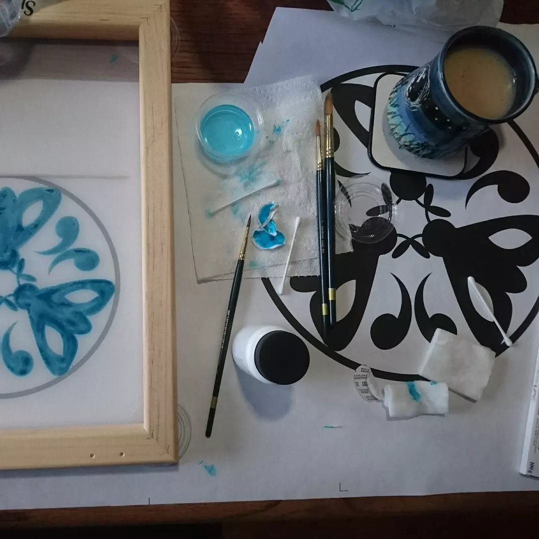 silk screen with moths painted on, white paper, paint brushes, water, and tea