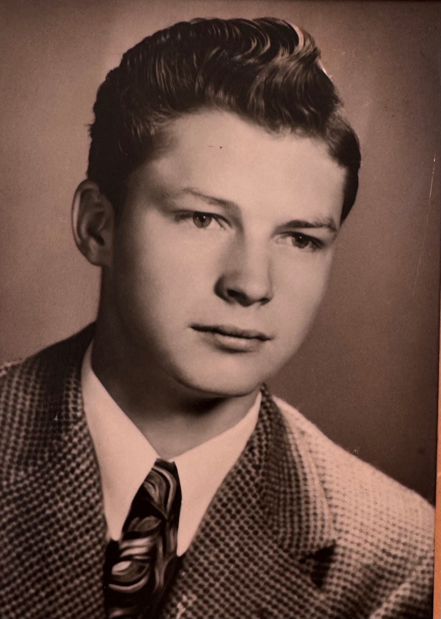 A black-and-white portrait of a handsome young white man wearing a dress shirt, tie, and tweed jacket.