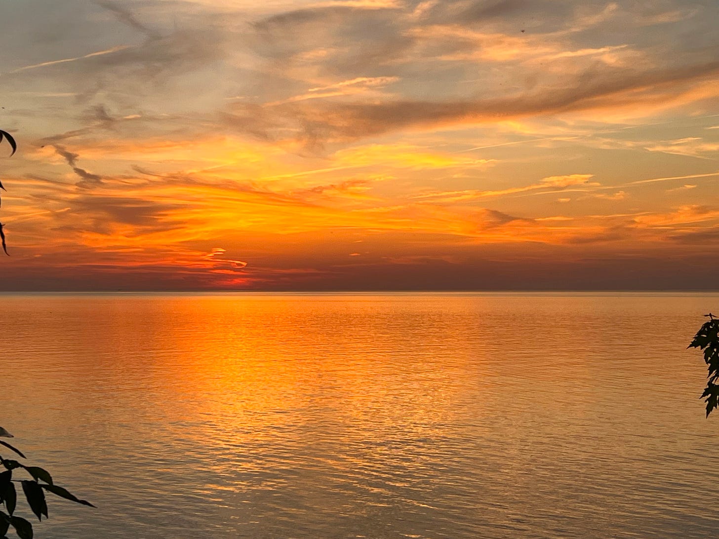 Sunset over a body of water with deep orange hues reflected Sunset over a body of water with deep orange hues reflected