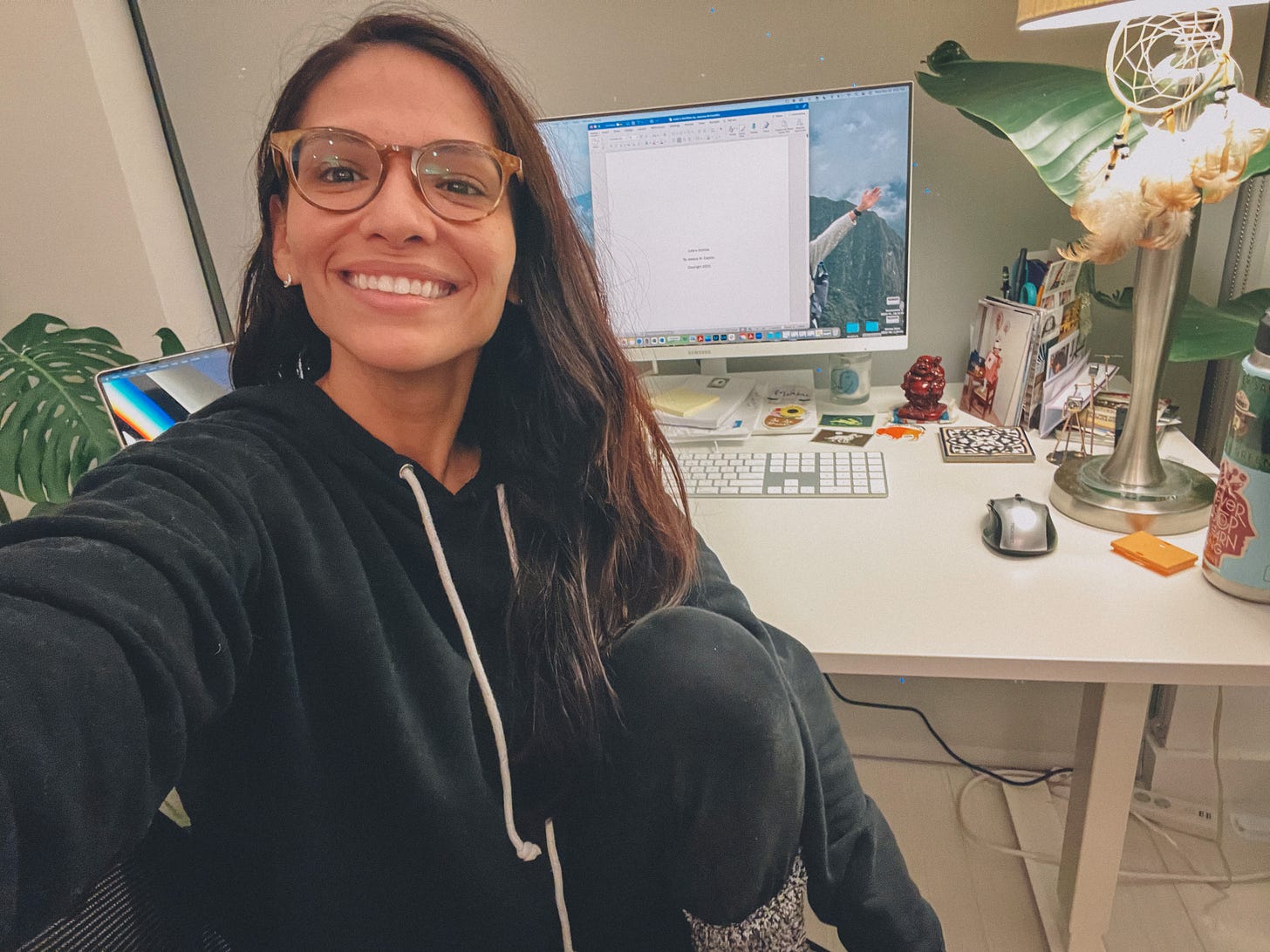 Selfie photo of woman with computer screen behind her, with title page of her novel.