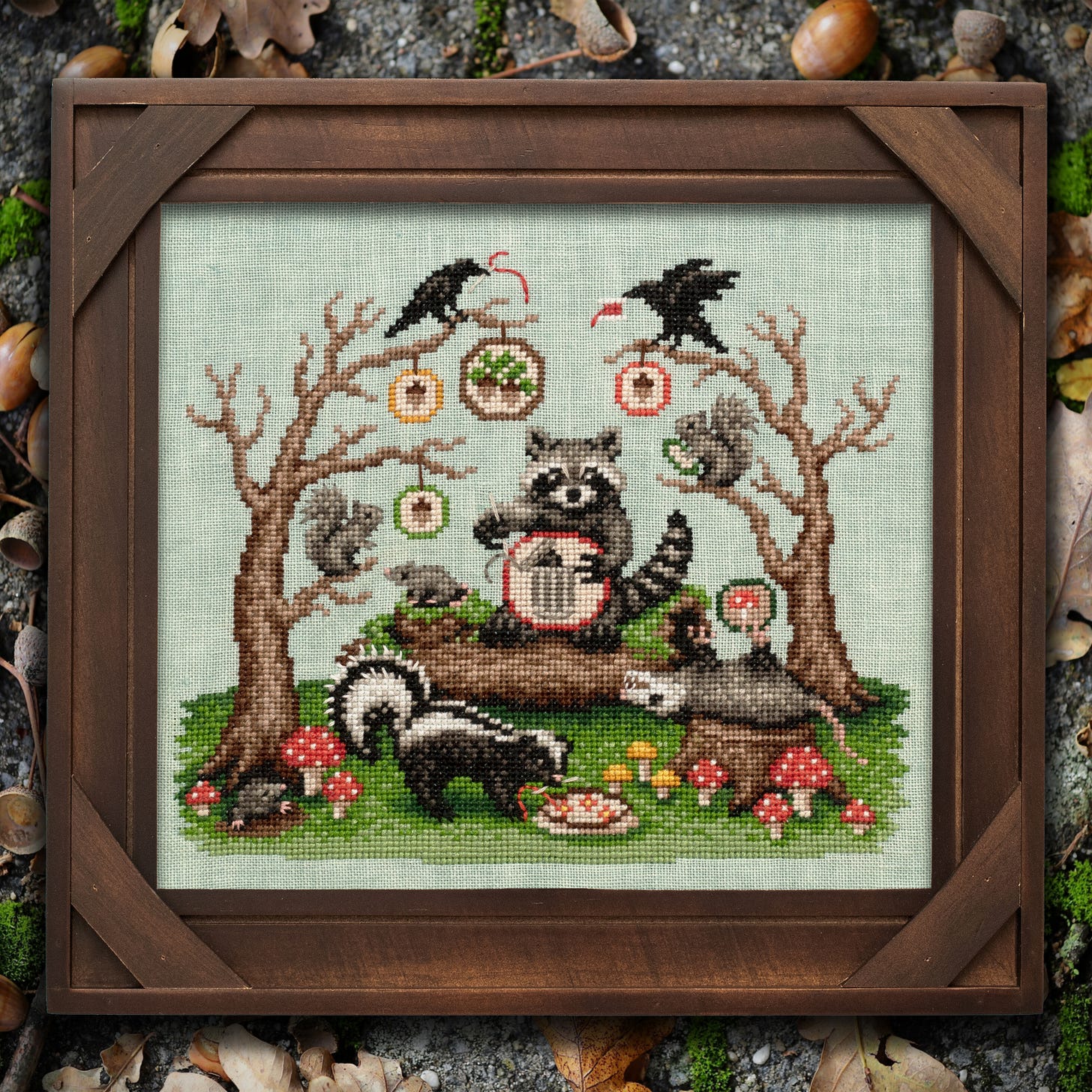A cross stitch of a racoonn cross stitching, crows in trees, a possum playing dead, and lots of cross stitch elements like hoops and stitching. A cross stitch of a racoonn cross stitching, crows in trees, a possum playing dead, and lots of cross stitch elements like hoops and stitching.