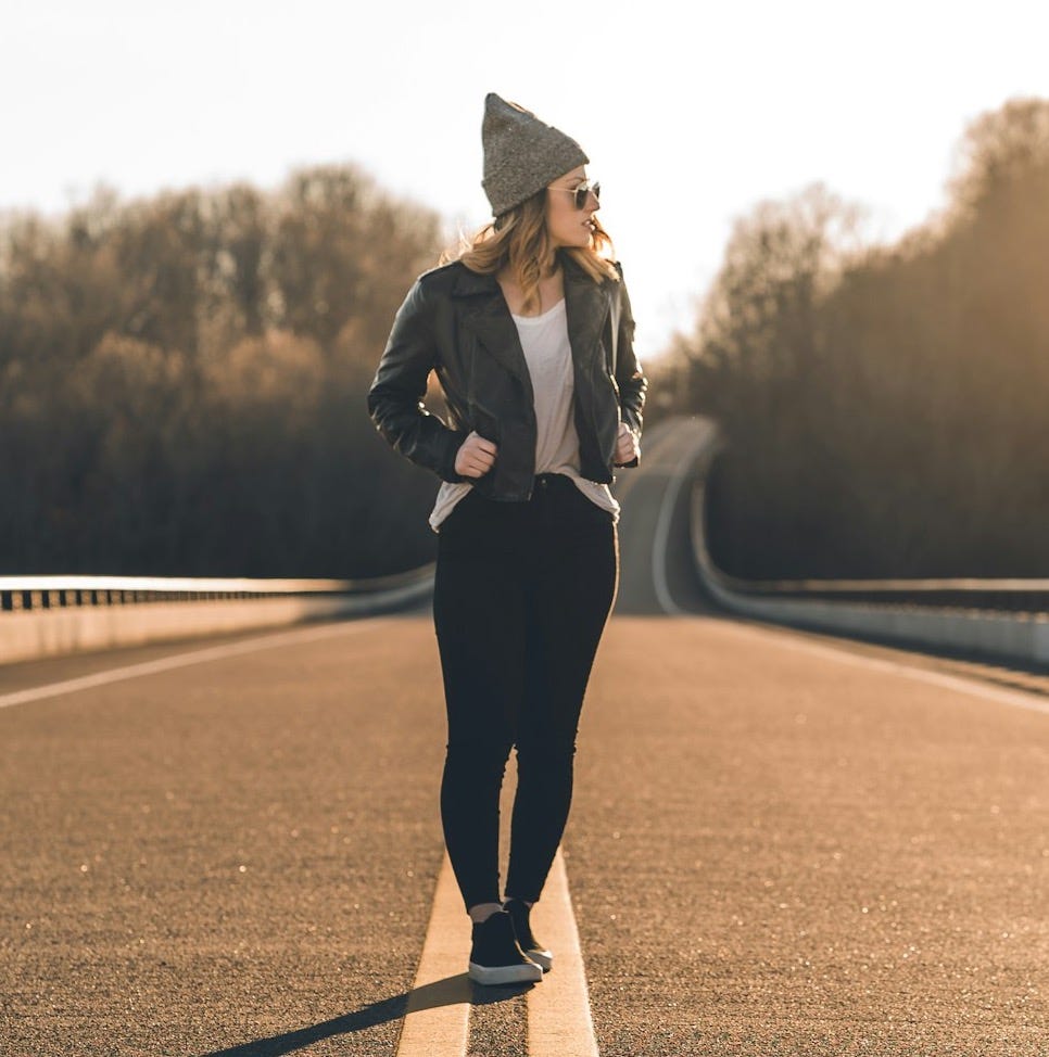 woman in black coat and black pants standing on road during daytime woman in black coat and black pants standing on road during daytime