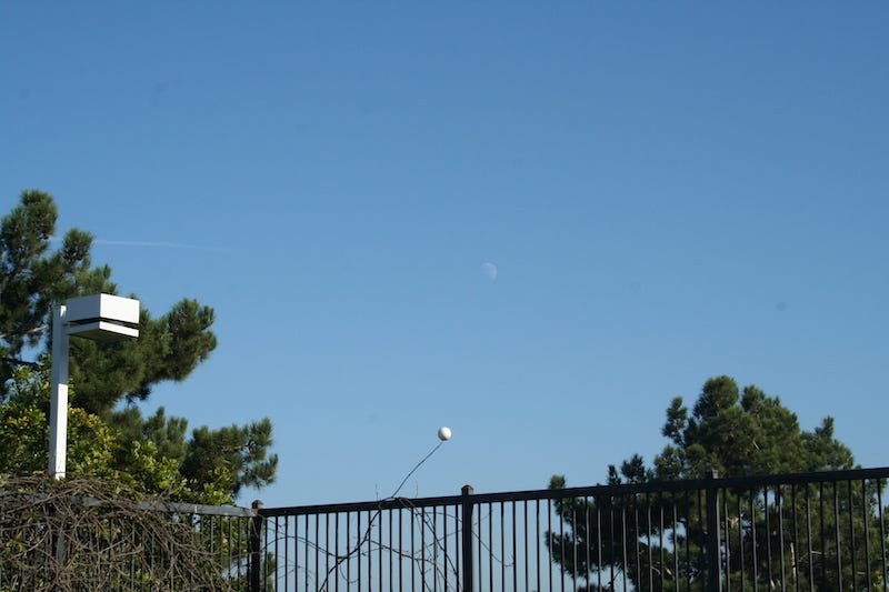 Comparison of the moon in the sky with a styrofoam ball, both seen in the same sunshine from the same angle, and both displaying a gibbous shape.