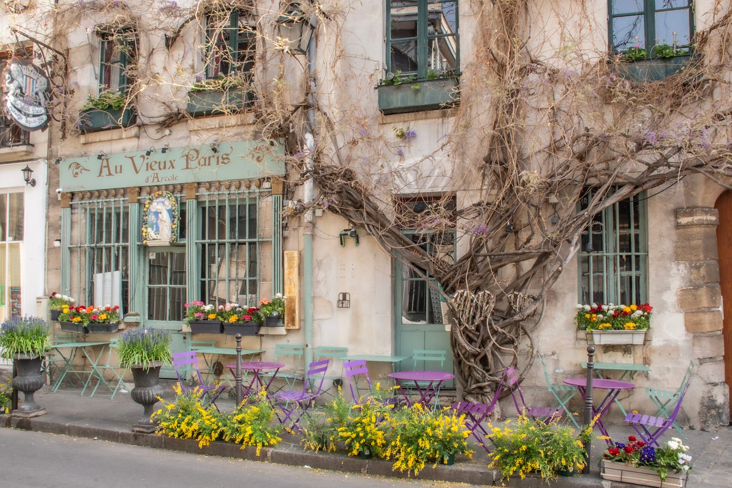 Au Vieux Paris d’Arcole café on Rue Chanoinesse with wisteria vines and colourful terrace tables