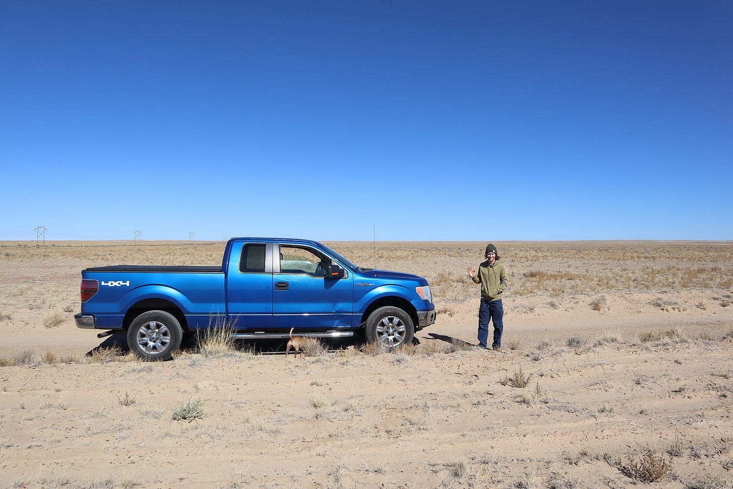 A man standing next to a truck in the middle of nowhere
