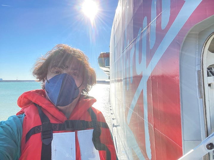 1st photo, me sat at an audio mixing desk in the ship's technology office. 2nd: Selfie on the deck in front of the Virgin logo on the chimney. 3rd: On my knees installing cabling in an access panel. 4th: Standing out on the open shell door at the starboard bow. I'm wearing life jacket and harnesses.