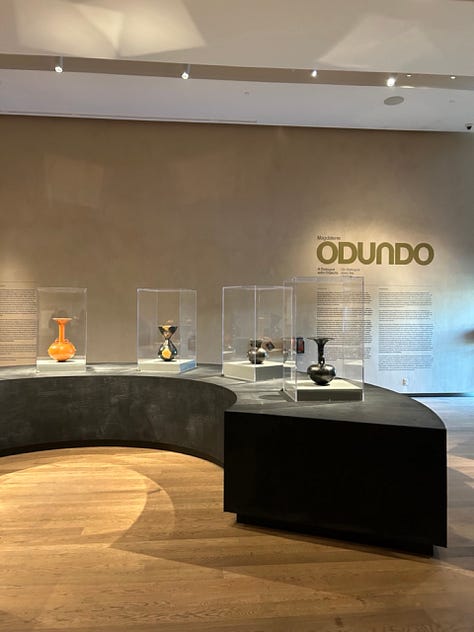 Musuem displays of pottery in glass cases, crafted headgear and