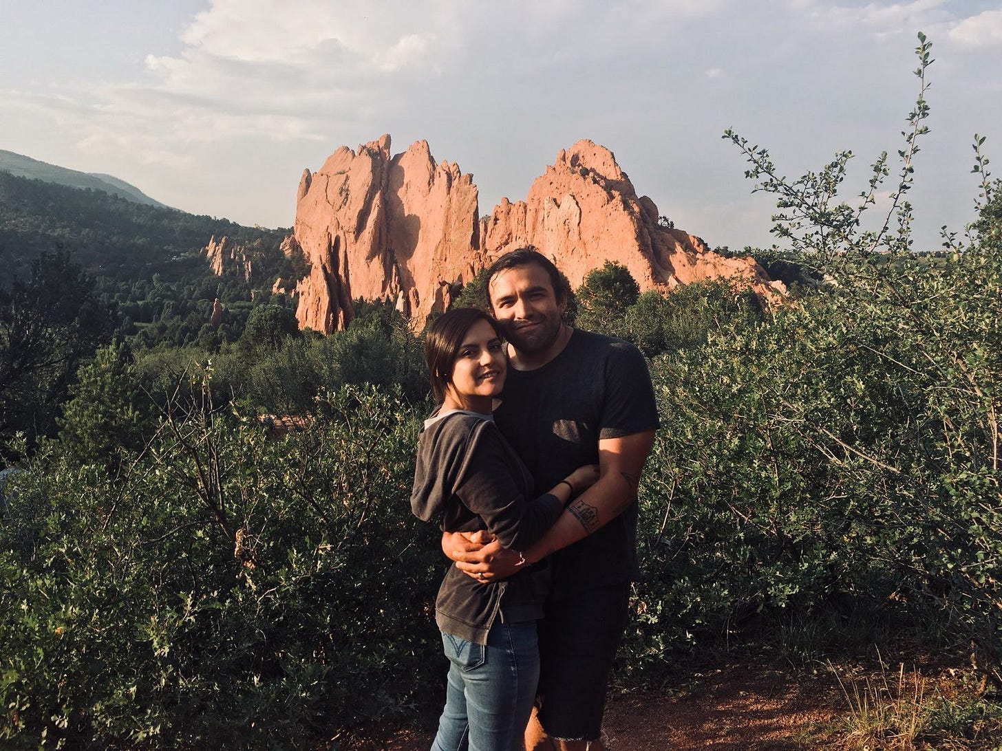 A couple holding each other standing in front of a rocky structure in the background. A couple holding each other standing in front of a rocky structure in the background.