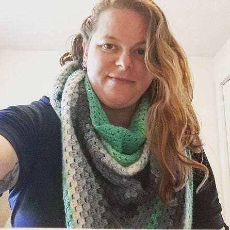 3 photos of the author wearing a crocheted scarf in Lion Brand Mandala "Genie" -- the colors are ombre teal, white and grey. In the second photo, the author is holding a mischievous grey and white kitten.