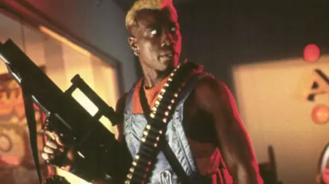 Wesley Snipes as badass psychopath Simon Phoenix in Demolotion man. He's sporting bleach blonde hair, a string vest and packing the biggest gun you've ever seen.