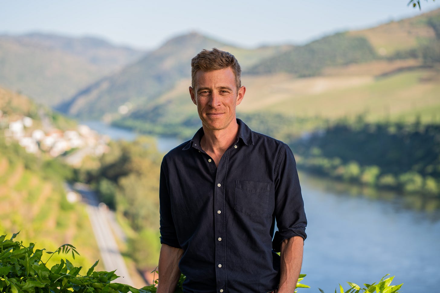 Photo shows a man posing for the camera with the Douro River and vineyards in the background. Photo shows a man posing for the camera with the Douro River and vineyards in the background.