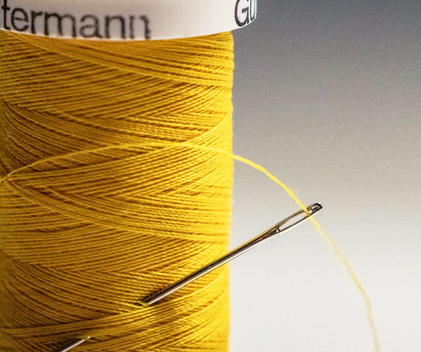 A spool of yellow thread with a needle stuck in it. 