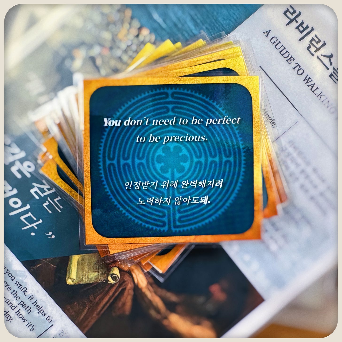 Close-up of stacked bilingual affirmation cards and a ‘Guide to Walking’ booklet; the top card reads ‘You don’t need to be perfect to be precious.'
