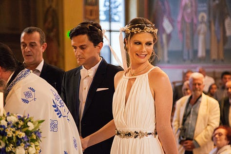 An American bride kisses a bible in a Greek Orthodox wedding ceremony, immediately regrets getting lipstick on it. The happy couple afterward at the beautiful candle-lit reception