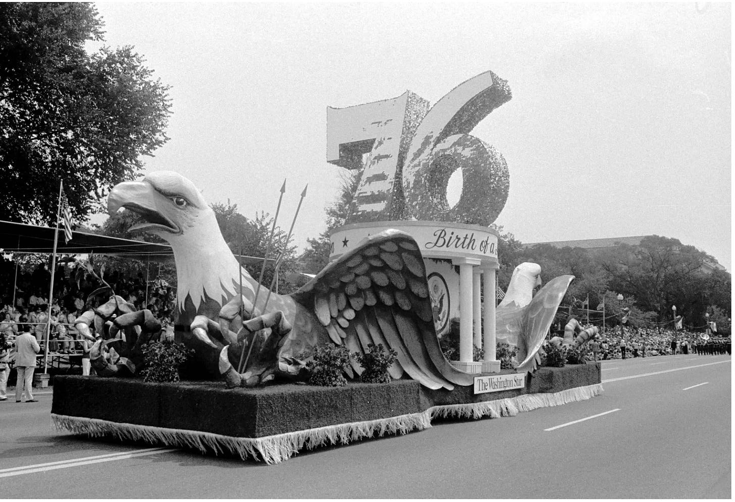 A black and white photograph of a float with a bald eagle and the numbers 76 that was part of the Bicentennial Parade in 1976 in Washington, DC.