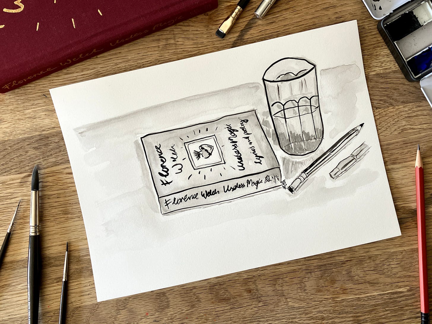 Painting of book and glass of water sits atop a table surrounded by art materials