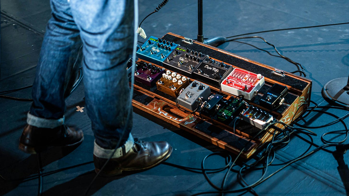 Person Standing on Wooden Floor with Scattered Pedalboards · Free Stock Photo Person Standing on Wooden Floor with Scattered Pedalboards · Free Stock Photo