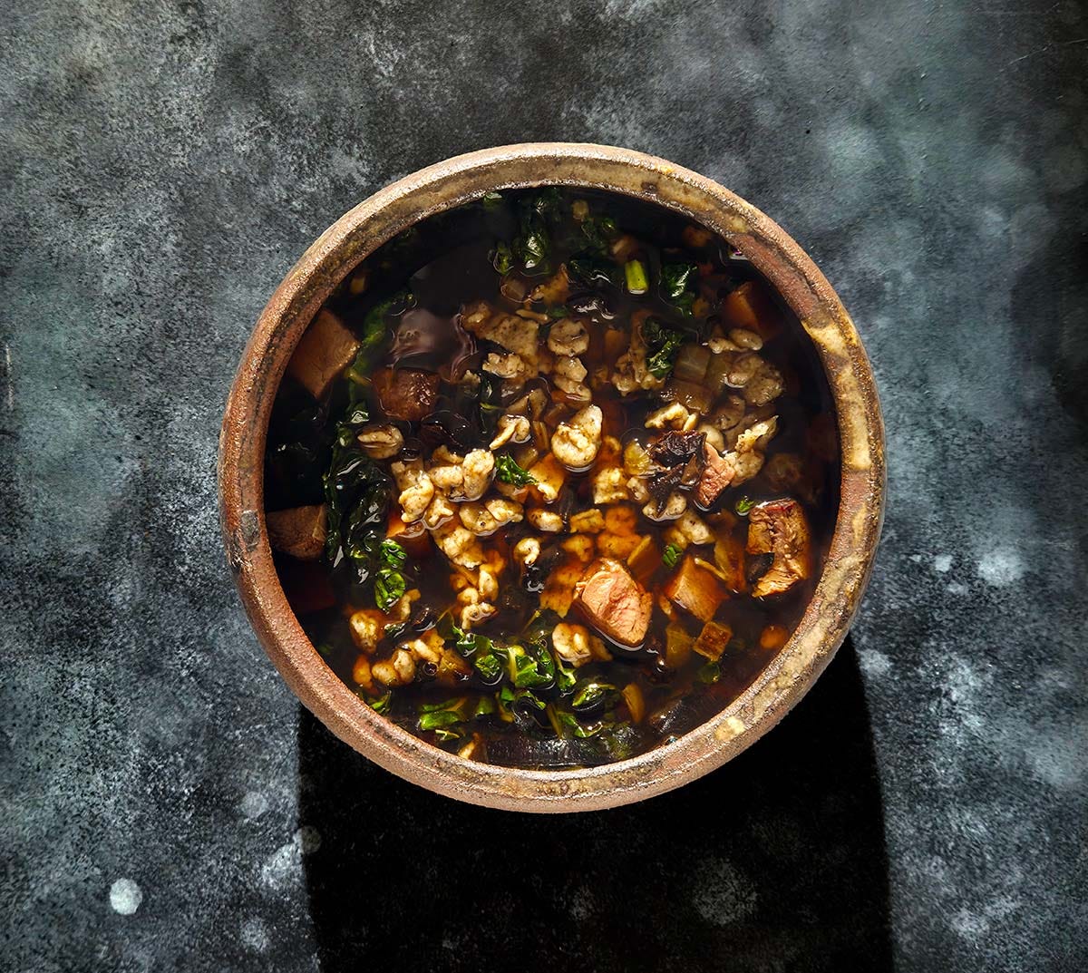 A bowl of soup on a dark background. 