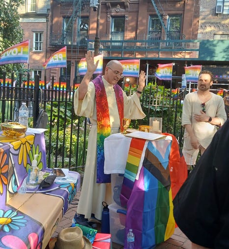 Father Eric Andrews, Pastor of Saint Paul the Apostle Catholic Church in New York City, celebrates Mass at the Stonewall National Monument surrounded by pride flags.