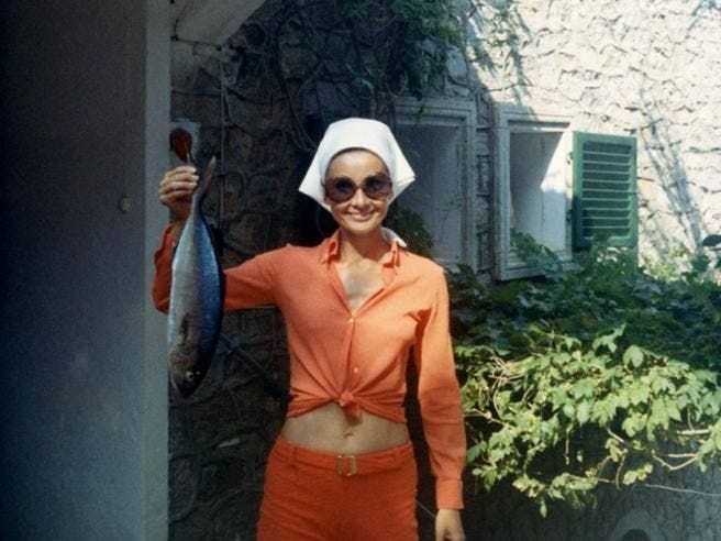 This may contain: a woman in an orange outfit holding a fish