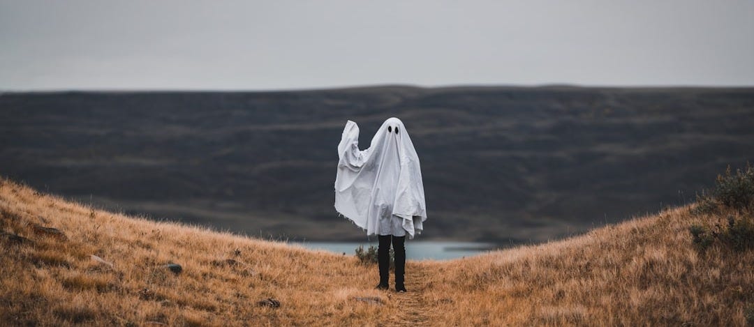 woman in white coat standing on brown grass field during daytime