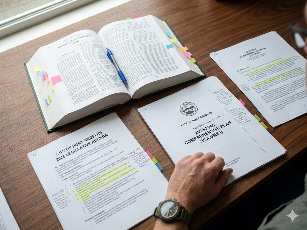 A conceptual, illustrative documentary photo looking down at a detailed work desk. An open physical volume of the Revised Code of Washington (RCW) is bookmarked with colorful notes. Next to it are highlighted copies of the 'CITY OF PORT ANGELES 2026 LEGISLATIVE AGENDA' and the 'STRATEGIC PLAN,' all featuring handwritten annotations, margin notes, and a blue pen.
