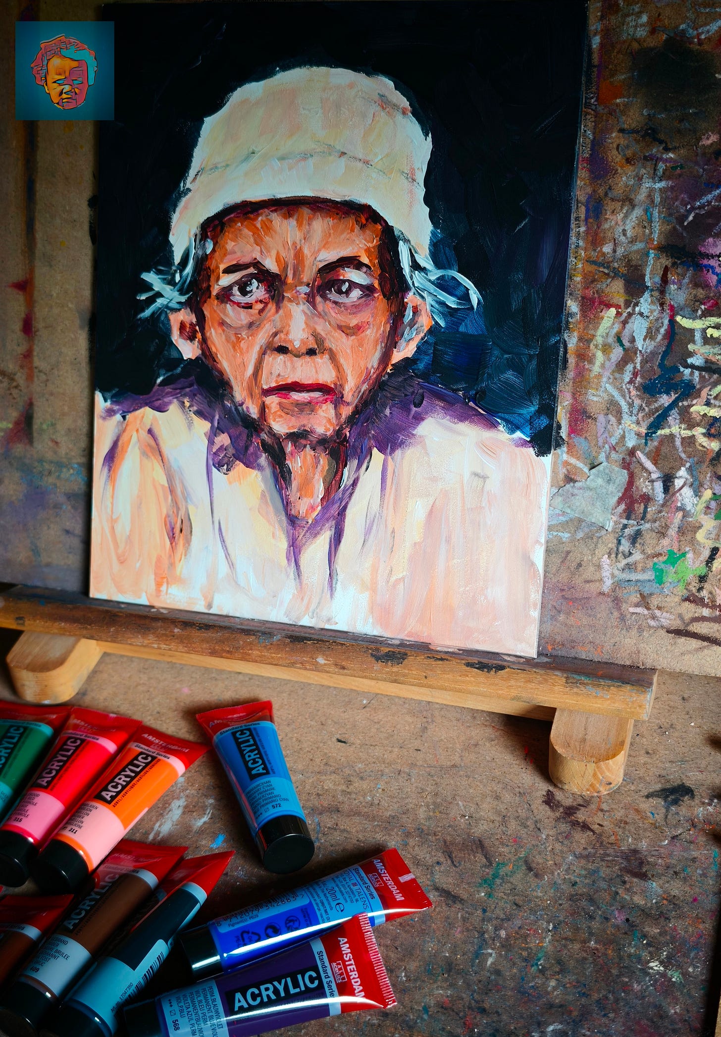 Schilderij van een oudere persoon met een lichte muts en een rimpelig gezicht, geschilderd met expressieve penseelstreken in oranje, paars en wit tegen een donkere achtergrond. Het doek staat op een houten schildersezel. Ervoor op de werktafel liggen tubes acrylverf in blauw, rood en oranje. Schilderij van een oudere persoon met een lichte muts en een rimpelig gezicht, geschilderd met expressieve penseelstreken in oranje, paars en wit tegen een donkere achtergrond. Het doek staat op een houten schildersezel. Ervoor op de werktafel liggen tubes acrylverf in blauw, rood en oranje.