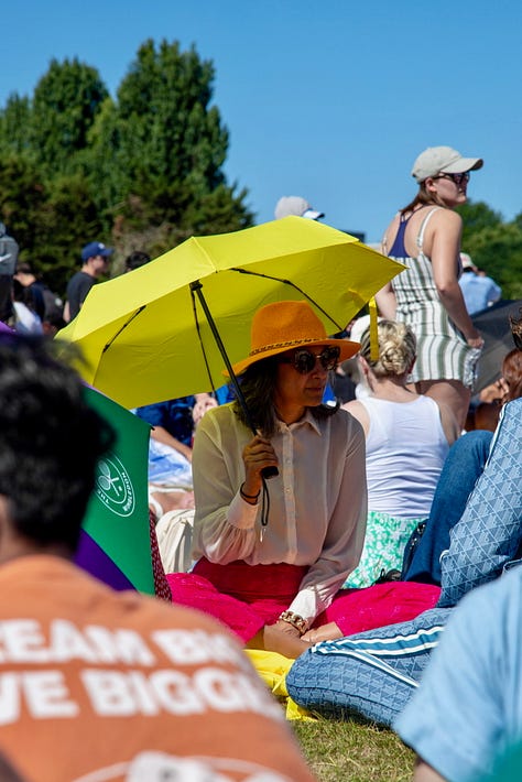 Three scenes from The Queue on a sunny day: a woman shading herself with a yellow umbrella, an ice cream truck with left luggage behind it, and a steward with a Wimbledon umbrella surveying the crowd
