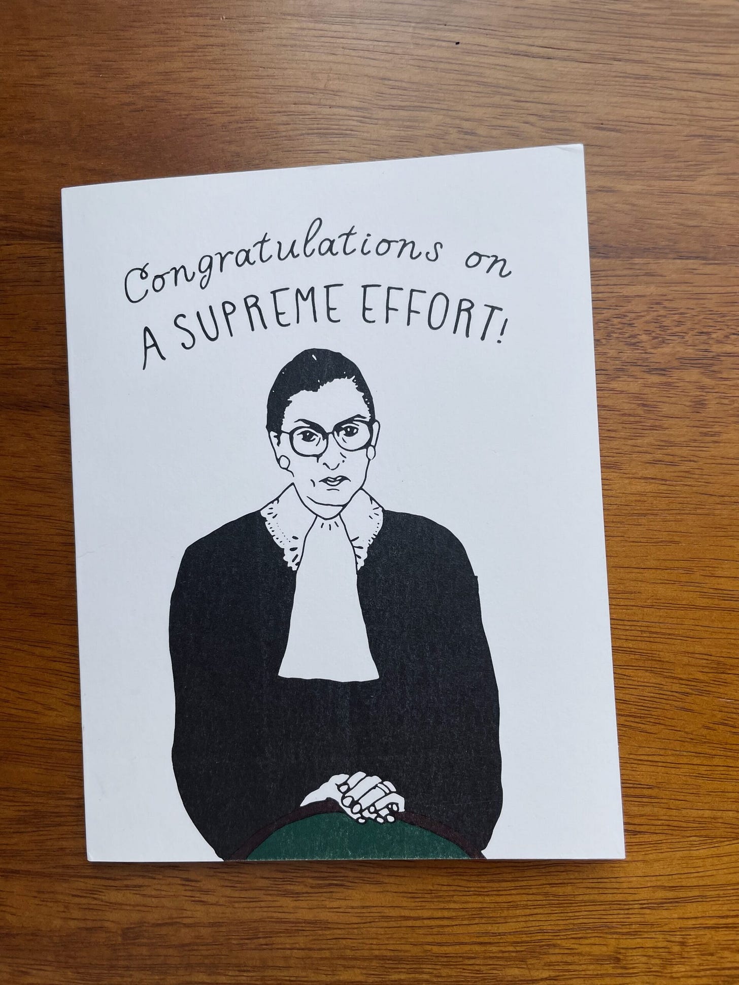 A printed card with a drawing of Justice Ruth Bader Ginsberg and the caption "Congratulations on a supreme effort!"