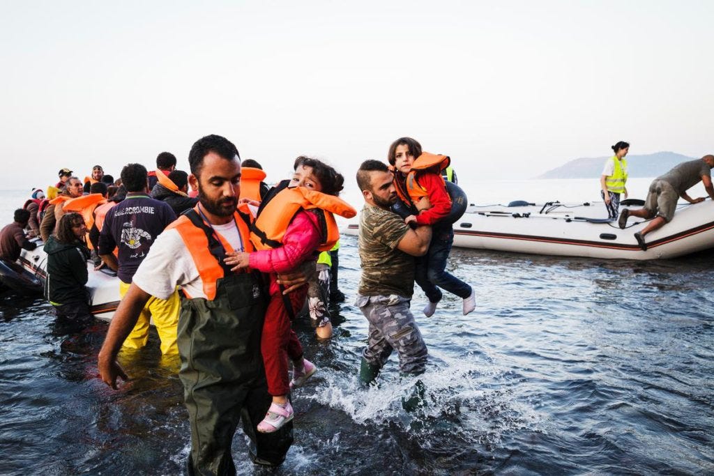 Locals carry two young girls to the shores of Lesbos, after they reached the island with their families in an inflatable boat full of refugees and migrants, having crossed the Aegean sea from Turkey. Locals carry two young girls to the shores of Lesbos, after they reached the island with their families in an inflatable boat full of refugees and migrants, having crossed the Aegean sea from Turkey.
