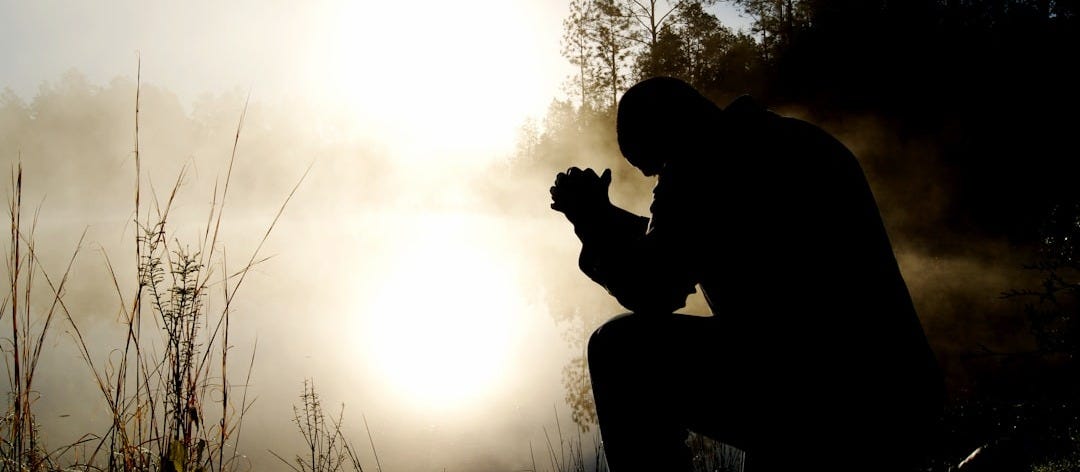 silhouette of kneeling man