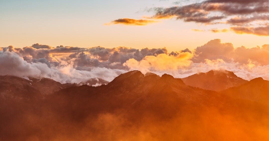 landscape photography of mountains with cloudy skies during golden hour