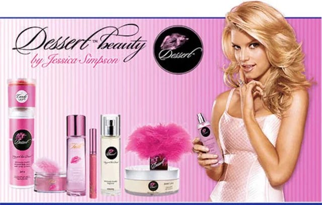 Jessica simpson holding a bottle from her edible skincare line Dessert Beauty with other products in the line displayed on a pink striped backdrop