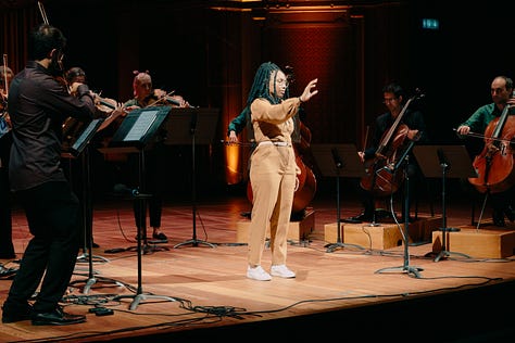 Actress Vilma Jackson, using sign language, standing in the middle of the stage, surrounded by United Strings of Europe musicians