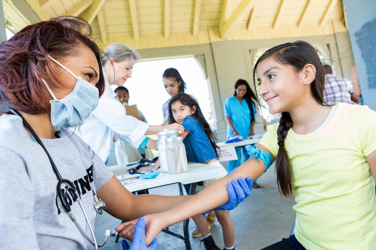 A healthcare worker administers care to a girl. A healthcare worker administers care to a girl.
