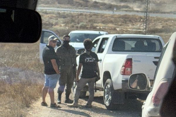 This photo taken by Congressman Ro Khanna's staffer Cameron Kasky captures armed settlers interacting with a member of the Israeli military. Khanna and Kasky said when they military arrived, they did not help clear their path, instead laughing, talking, and smoking with the settlers. (Credit: Cameron Kasky)