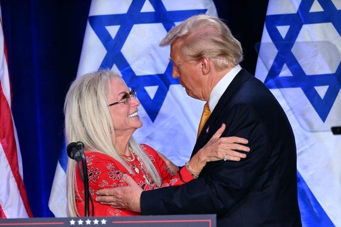 Miriam Adelson embraces Donald Trump with Israeli flags in the background.