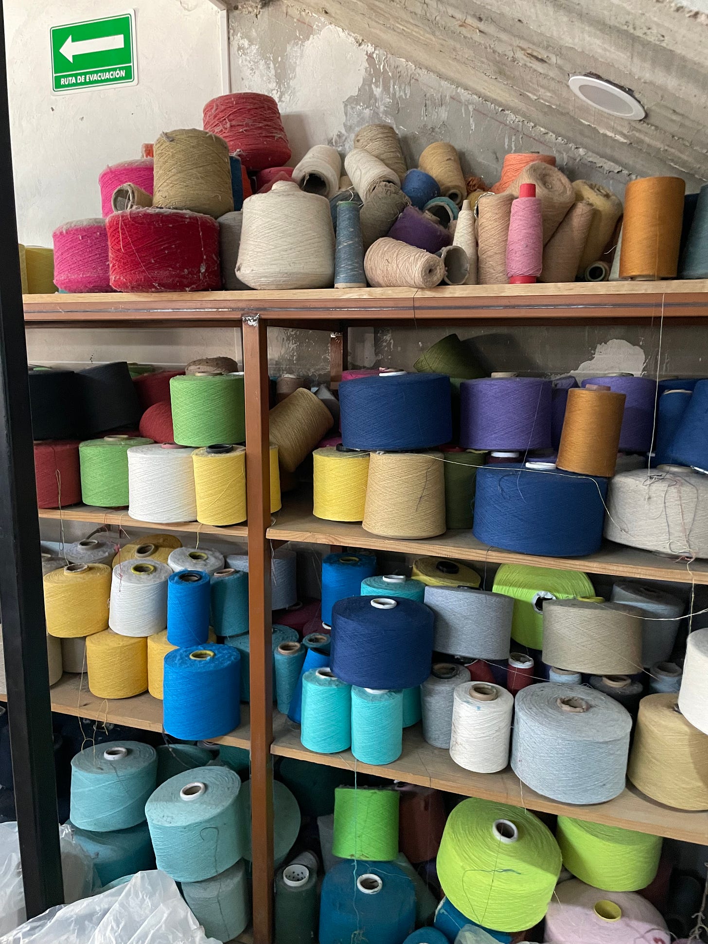 Many spools of different colored thread on a shelf.