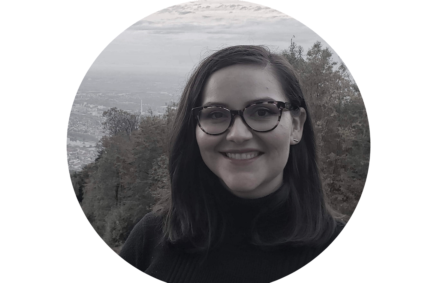 A black and white photo of a woman with shoulder length dark hair. She is wearing glasses and smiles at the camera A black and white photo of a woman with shoulder length dark hair. She is wearing glasses and smiles at the camera