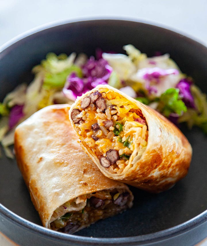 Rice and bean burrito and a burrito bowl with grated cheese and toppings.