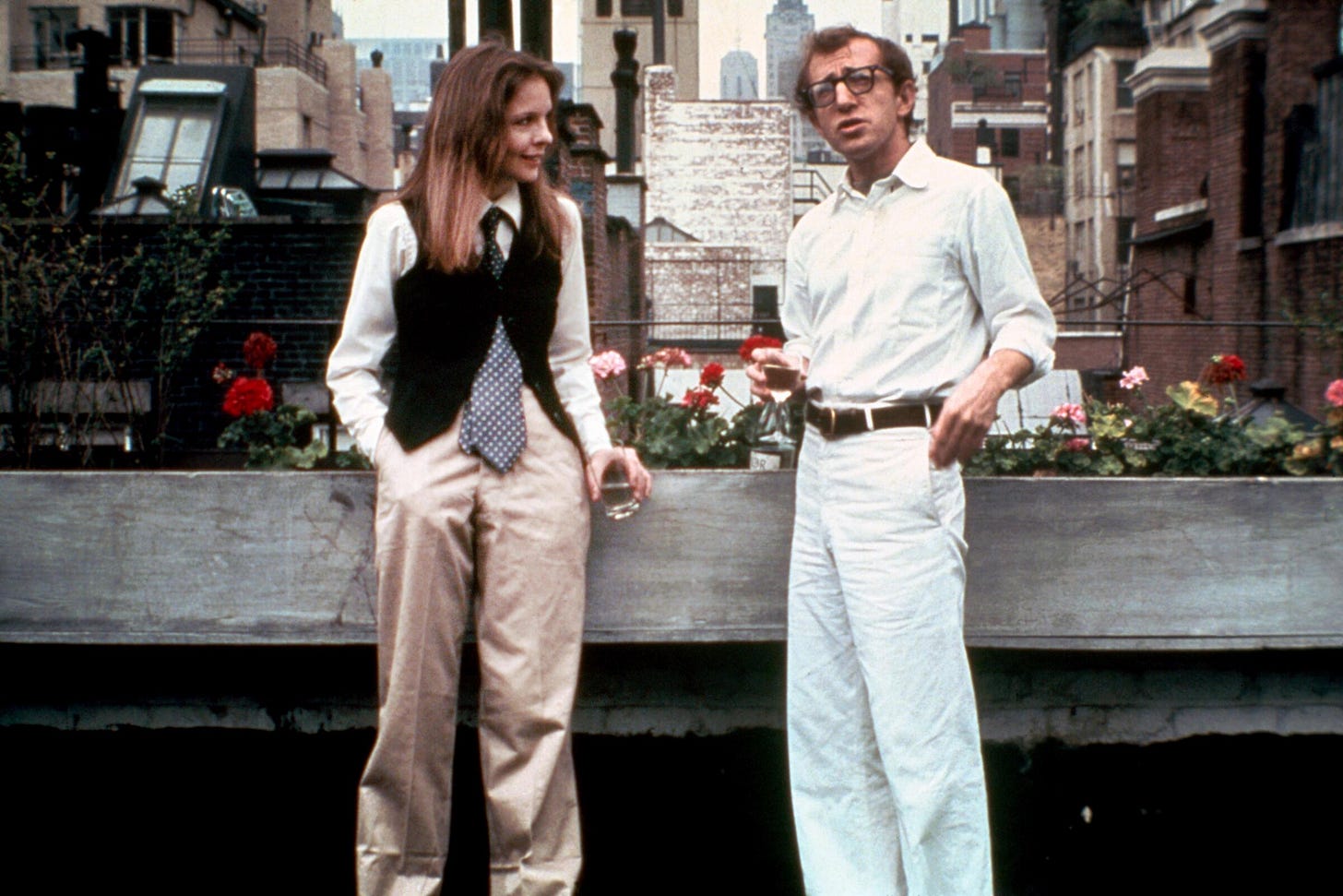 Diane Keaton wearing a vest, tie, baggy khaki pants, and Woody Allen in white chinos and a white shirt, stand on a terrace in Manhattan. Diane Keaton wearing a vest, tie, baggy khaki pants, and Woody Allen in white chinos and a white shirt, stand on a terrace in Manhattan.