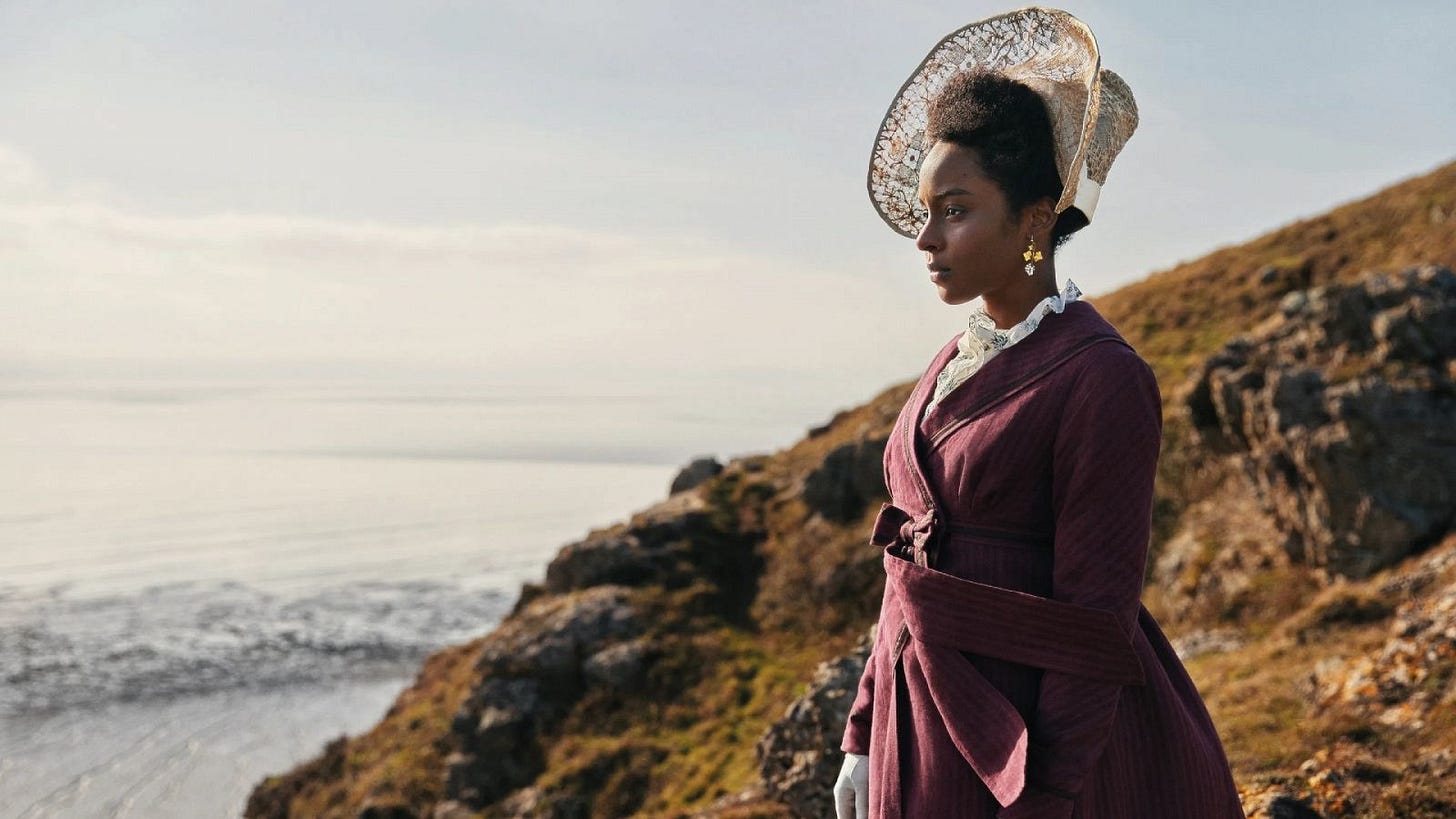 Regency-era woman standing on a cliff and looking out toward the sea. 