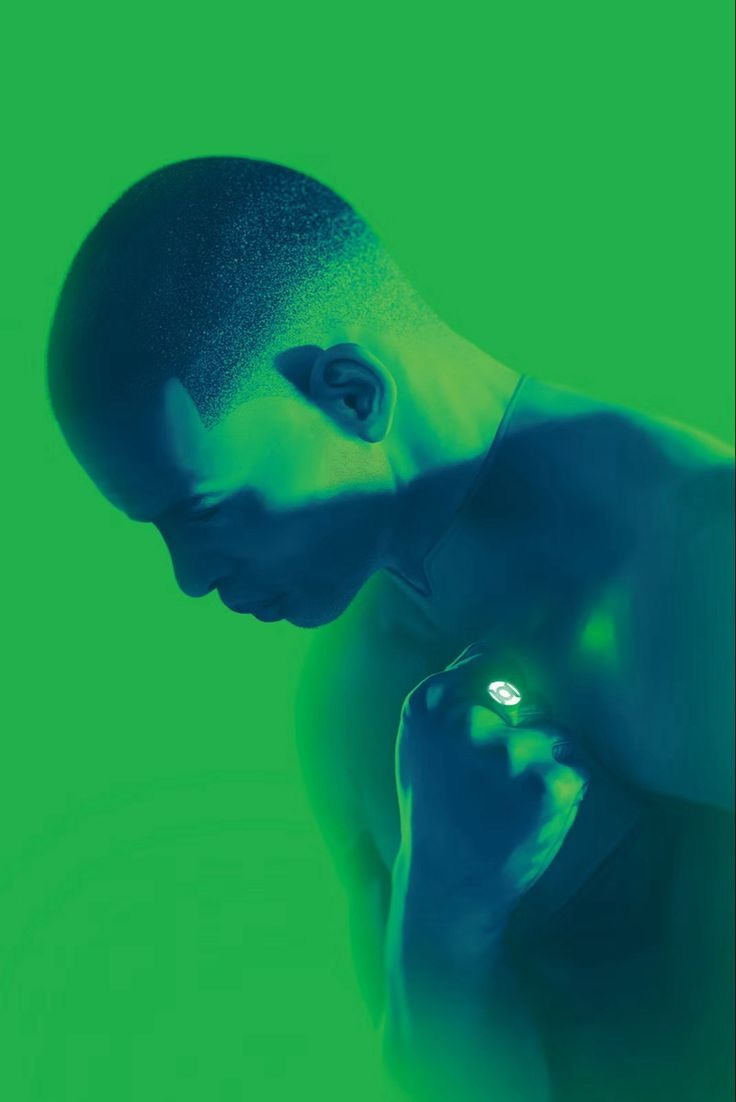 This may contain: a man with his hands on his chest in front of a green background, holding a cell phone