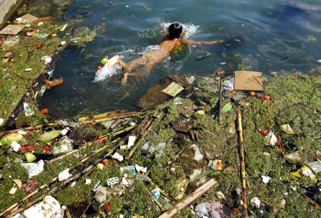 A child swims in a polluted reservoir in Pingba, southwest China's Guizhou province September 2, 2006. Photo by China Daily/Reuters