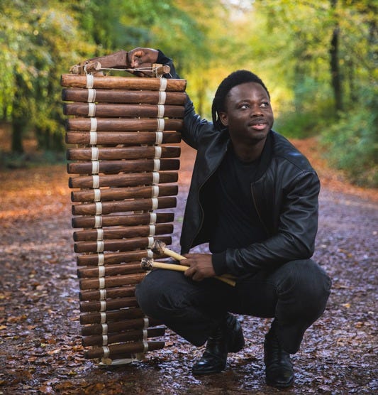Nfamady Kouyate - Photo by Nadine Ballantyne. Nfamady holding a balafon vertically.