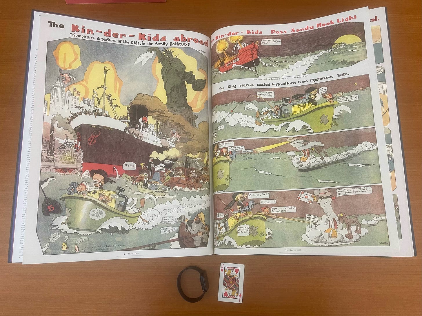 A spread from the enormous Sunday Press Books’ Forgotten Fantasy: Sunday Comics 1900-1910 with my watch and a playing card underneath it for scale.  Spread open, the book is two feet high and about 2.5 feet wide. We see two color pages of The Kin-der-Kids by the German artist Lyonel Feininger.