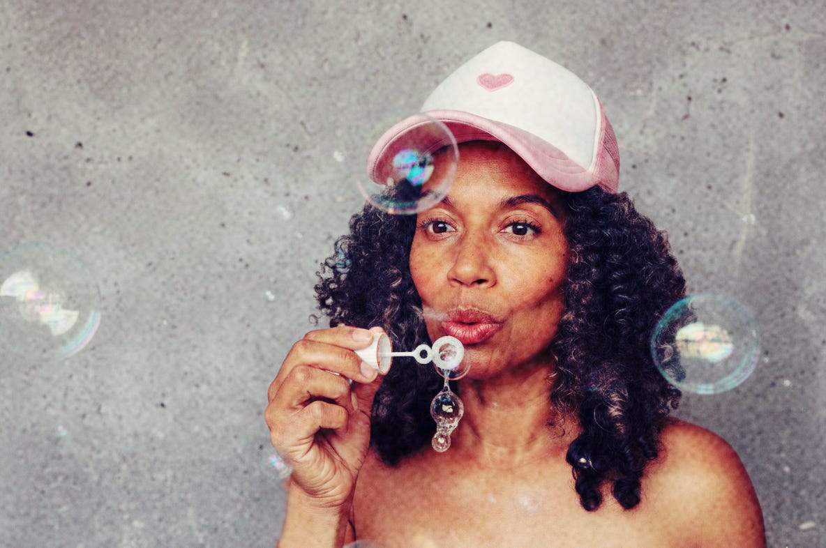 A woman blowing bubbles against a textured gray backgroundârepresenting the clarity and 'soap' needed to wash out the status quo. A woman blowing bubbles against a textured gray backgroundârepresenting the clarity and 'soap' needed to wash out the status quo.